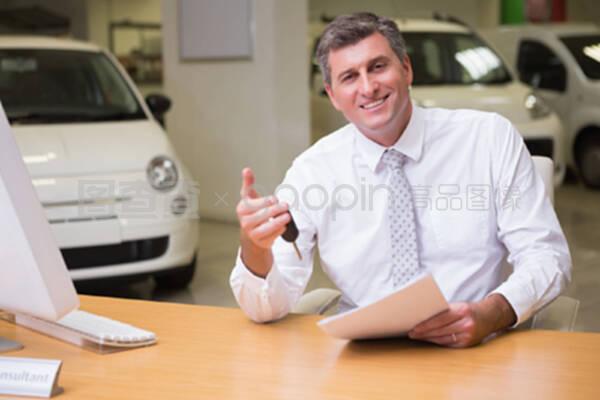 微笑的推销员拿着车钥匙和文件